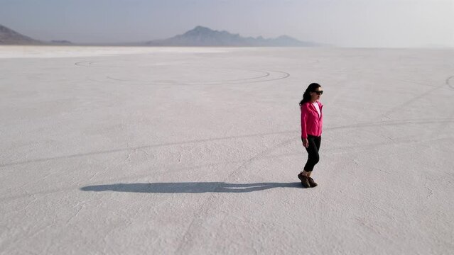 Aerial shot of an Asian woman hiking across the Bonneville Salt Flats flats in Utah