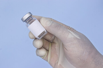 Hand with white glove holding medical vial or vaccine vial on bl