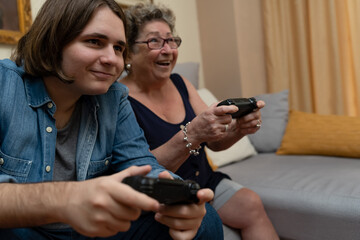 Grandma and grandson having fun playing video games at home.