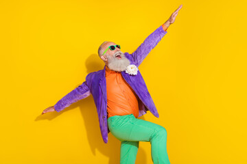 Photo of cool attractive guy dressed violet velvet jacket rising hands sides dancing disco isolated yellow color background