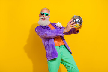 Photo of cheerful funky man wear purple velvet jacket rising discotheque ball dancing isolated...