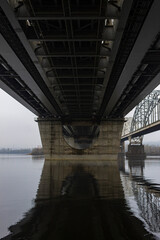 Under the bridge across the river and it's reflection at the water