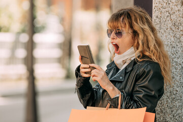 shopping woman with mobile phone and surprised expression