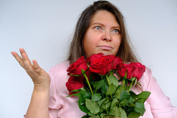 bouquet of flowers, red roses, middle-aged woman 50 years old with bulging eyes from bewilderment and surprise, dissatisfaction with gift, flower pollen allergy, close-up emotional female portrait