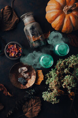 Witchcraft still life concept with smoking potion, herbs ingredients candles and magical equipment