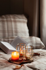 warm cozy bedroom winter or autumn concept, candles on tray and a book