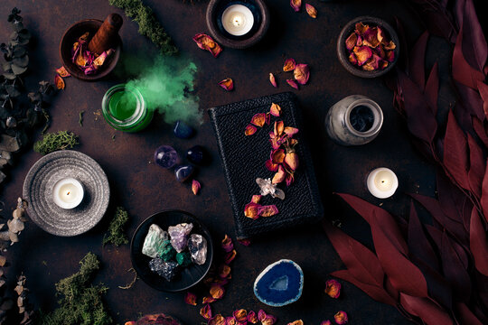 Witchcraft still life concept with smoking potion, spell book, herbs ingredients candles and magical equipment