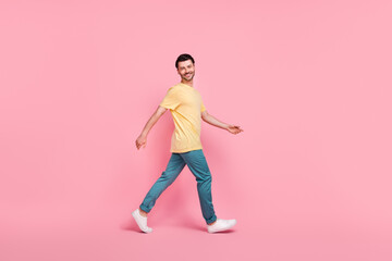 Fototapeta na wymiar Full length photo of optimistic attractive man dressed comfort clothes going moving empty space isolated on pink color background