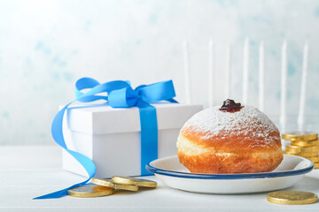 Happy Hanukkah. Hanukkah sweet doughnuts, gift boxes, white candles and chocolate coins on white wooden background. Image and concept of jewish holiday Hanukkah. Top view.
