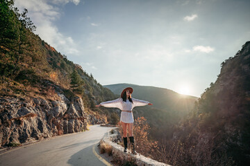 Traveler woman in brown hat and white sweater looking at amazing mountains and forest, wanderlust...