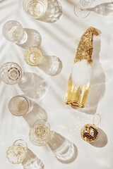 New Year party flatlay, white sparkling wine, crystal glasses, champagne bottle, dwarf dress, cap and beard, mirror ball, beige aesthetic layout, new year holiday event concept, sunshine shadow