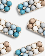 Colorful Easter eggs in carton packing, blue, beige, white neutral colors, festive chicken egg in paper container as pattern on grey background. Minimal style aesthetic layout, geometric design