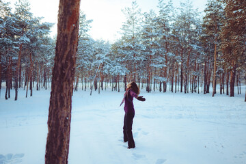 Young woman enjoying winter weather in the snow forest.