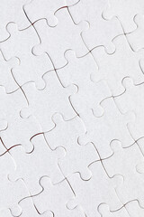 White jigsaw puzzle pieces. Fill in pieces of the jigsaw puzzle. Complete the jigsaw puzzle with the missing pieces. Fragment of a folded white jigsaw puzzle.