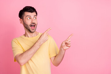Portrait of impressed astonished positive man wear yellow t-shirt directing empty space open mouth isolated on pink color background
