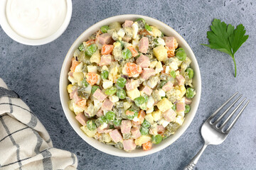Russian Olivier salad of vegetables, sausage and mayonnaise on a gray background. Top view. Selective focus.	