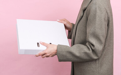 Business woman in a woolen coat holding white folder mockup on pink background