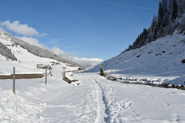 Footpath in snow near a stream, on a sunny day in Austrian Alps