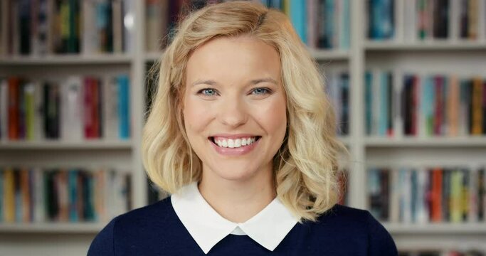 Student face of a young woman student smiling and laughing while standing in a library at university. Portrait of cheerful female, happiness and university campus or college room with smile in Sweden