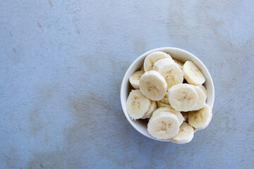 Bowl full of banana slices on an abstract background. Concept of healthy food, fruits.