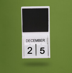 Wooden calendar with December 25 date levitating on green background.