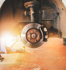 Disc brakes and calipers that remove the wheels of a car in the auto repair garage with sunlight.