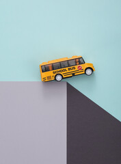 Toy school bus on a paper cube. Optical illusion. Geometric composition. Minimalistic creative...