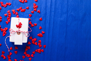 Wrapped box with present and empty tag and many red little hearts  on  electric blue textured  paper background.  Place for text. Top view. Romantic postcard.. - 550666669