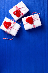 Boxes with presents with hearts  on   bright  blue textured  paper background.  Place for text. Top view. Romantic postcard. - 550666683