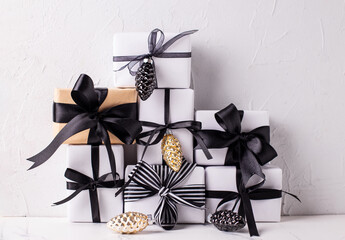 Black, white and gold Christmas. Set of wrapped boxes with presents and golden decorative cones against white textured  wall. Scandinavian style. Place for text.. - 550666803