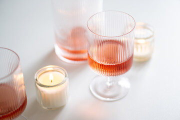 Rose wine in trendy ribbed wineglasses and decanter on white table