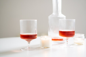 Rose wine in trendy ribbed wineglasses and decanter on white table