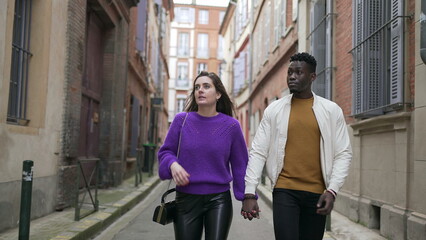 Fototapeta na wymiar Young interracial couple walking holding hands. Modern millennial couple