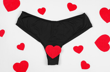 Black women's panties with a red heart on a white background. The concept of underwear made from natural fabrics. Women's health care