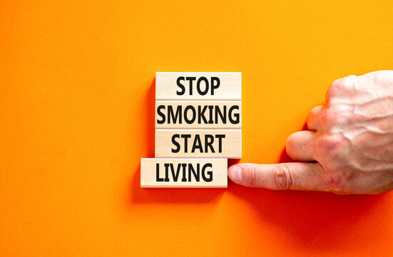 Stop smoking start living symbol. Concept words Stop smoking start living on cubes. Beautiful orange background. Doctor hand. Medical healthy lifestyle stop smoking start living concept. Copy space.