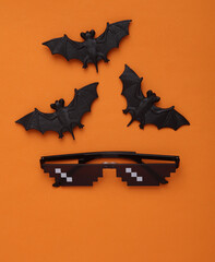Bats with pixel sunglasses on an orange background. Halloween concept