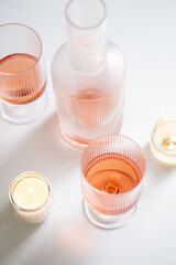 Rose wine in trendy ribbed wineglasses and decanter on white table