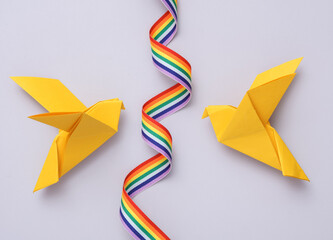Yellow origami doves with rainbow ribbon on a gray background. Peace symbol, no war