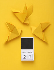 World Peace Day. Origami Dove and calendar with date september 21, yellow background