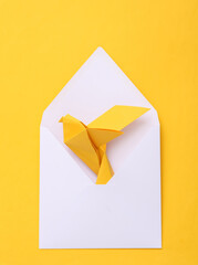 Origami carrier dove in white envelope on yellow background