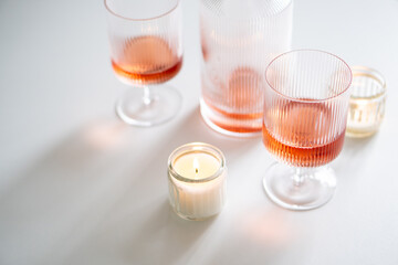 Rose wine in trendy ribbed wineglasses and decanter on white table