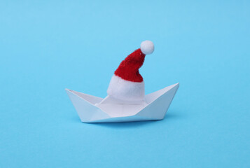 Paper boat with santa hat on blue background