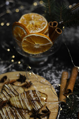 christmas decoration of dried pears in chocolate on a wooden stand of cinnamon oranges and Christmas tree branches on a dark background. for postcards menu labels calendars signs and stands