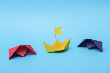 Paper colored boats on a blue background. Business, leadership concept