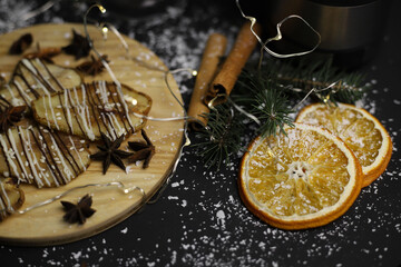 christmas decoration of dried pears in chocolate on a wooden stand of cinnamon oranges and Christmas tree branches on a dark background. for postcards menu labels calendars signs and stands