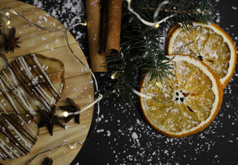 christmas decoration of dried pears in chocolate on a wooden stand of cinnamon oranges and Christmas tree branches on a dark background. for postcards menu labels calendars signs and stands