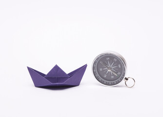Leadership, pursuit of goals, navigation, business concept. Paper boat and compass on a blue background