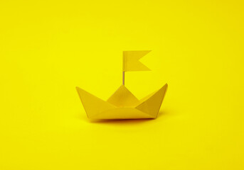 Naklejka premium Yellow Paper boat with flag on yellow background. Leadership concept
