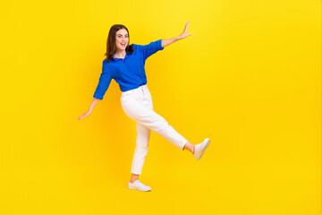 Fototapeta na wymiar Full length photo of sweet shiny lady wear blue shirt dancing walking empty space isolated yellow color background
