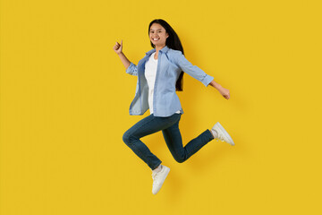 Glad happy cute millennial korean lady student in casual jumping and freezing in air enjoy freedom,...